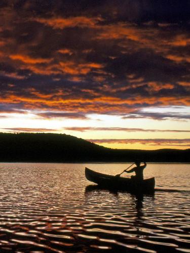 a lone canoeist paddles out onto Round Pond on the Allagash Wilderness Waterway in northern Maine