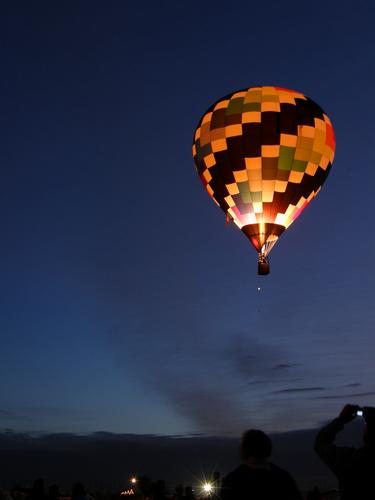 a dawn-patrol hot-air balloon is silhouetted against the pre-dawn sky at the Albuquerque Balloon Festival in New Mexico