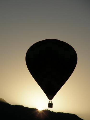 the sun rises behind an early-morning-launched balloon at the Albuquerque Balloon Festival in New Mexico