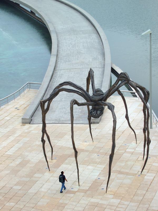 a tourist approaches the giant spider outside the Guggenheim Museum at Bilbao in Spain