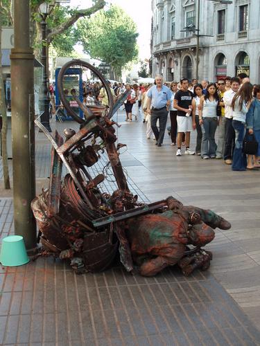 a street mime fakes an elaborate bike crash for the tourist flow along La Rambla at Barcelona in Spain