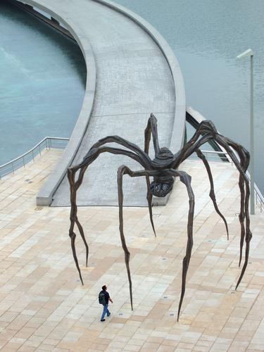 a tourist approaches the giant spider outside the Guggenheim Museum at Bilbao in Spain