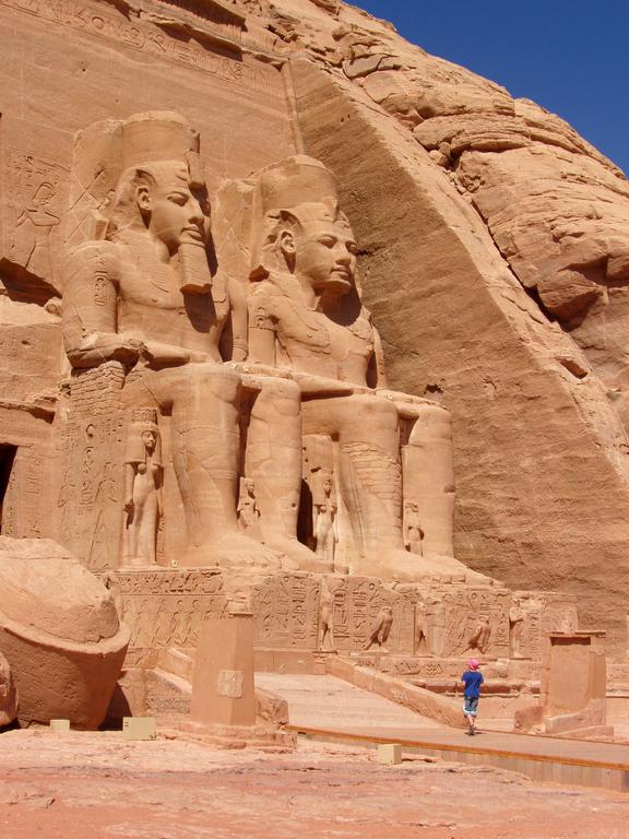 a young tourist looks up at the famous statues of Ramses II at Abu Simbel in Egypt