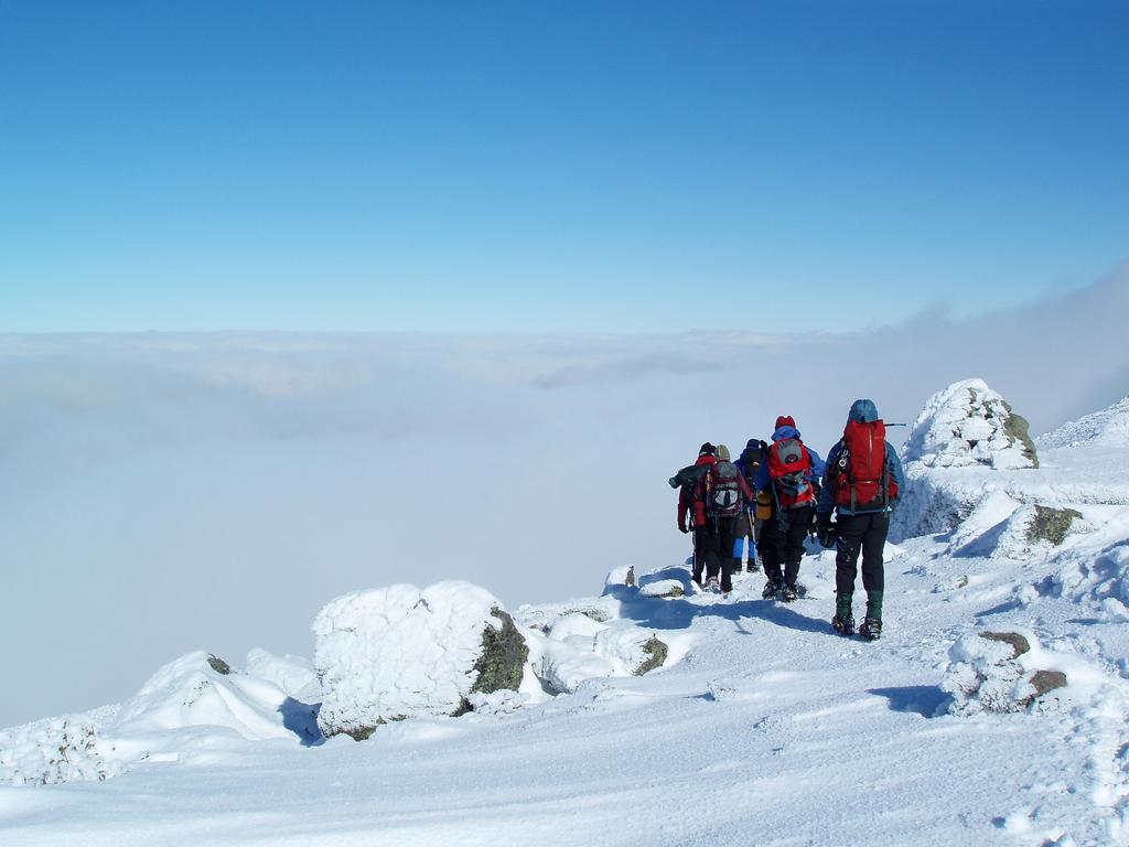 winter hikers descend from Mount Adams in New Hampshire toward an undercast cloud layer
