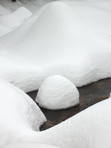 deep snow covers a brook on Big Attitash Mountain in New Hampshire