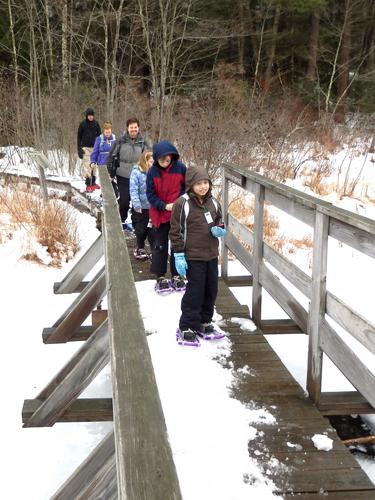winter hikers on Bouchard Bridge at Beaver Brook in New Hampshire