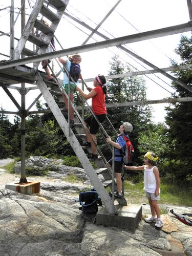 hikers climbing the tower atop Belknap Mountain in New Hampshire