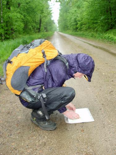 hiker in the rain checking map-and-compass