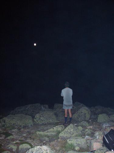 Ed looks up at the moon in the dark night sky on Bondcliff Mountain in New Hampshire