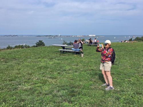 Andee takes a panorama photo fromt he open northern summit of Spectacle Island at Boston Harbor in Massachusetts