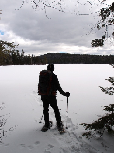 winter bushwhacker at the shore of Spoonwood Pond on the way to Cabot Preserve Peak in New Hampshire