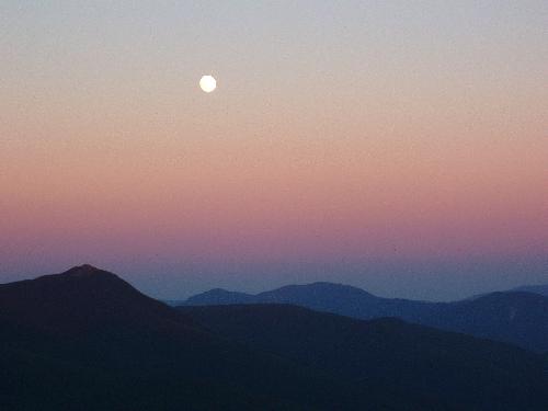 the full moon rises above Mount Liberty as seen from Cannon Mountain in New Hampshire