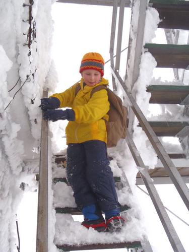 young hiker on the summit tower steps atop Mount Cardigan in New Hampshire