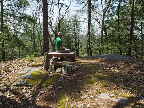 hiker at the summit bench on Mount Cresson at Swanzey in southwestern New Hampshire