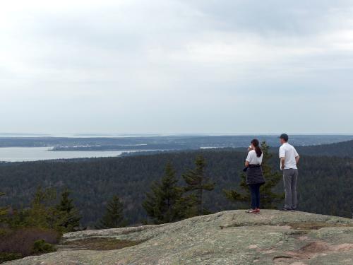 a pair of hikers checks the view near the summit of Day Mountain at Acadia National Park in Maine
