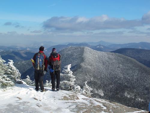 two hikers check the winter view from Mount Osceola in New Hampshire