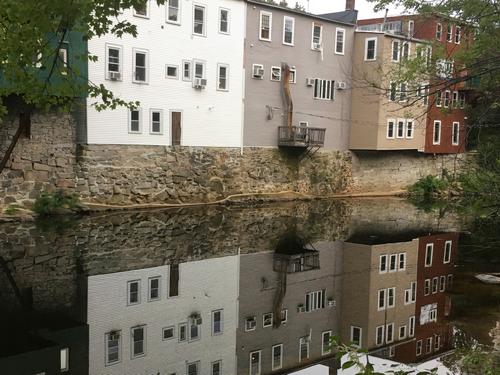 reflection on the Souhegan River of buildings on the Milford Oval near Federal Hill in southern New Hampshire