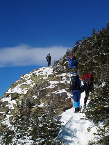 winter hikers ascend toward the summit of Mount Flume in the White Mountains of New Hampshire