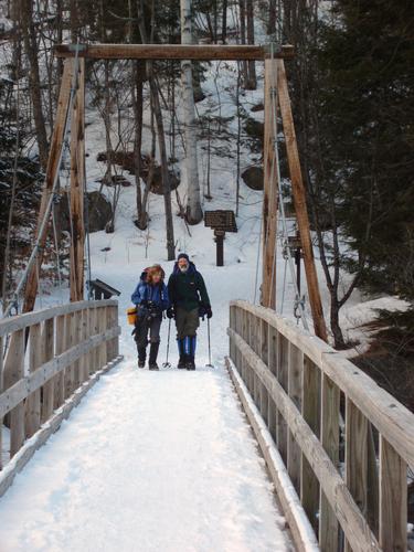 winter hikers crossing the Lincoln Woods suspension footbridge in New Hampshire
