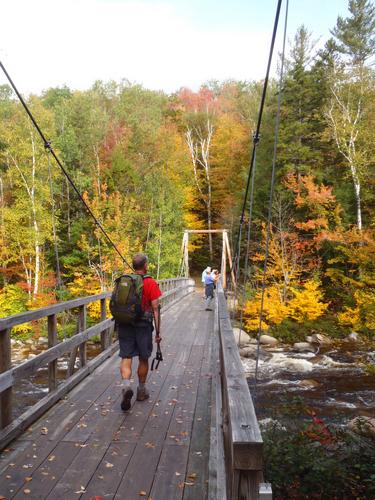 hiker crossing the suspension footbridge on the way to Mount Flume in New Hampshire