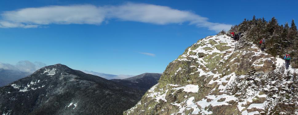 with Mount Liberty in the background, winter hikers ascend toward the summit of Mount Flume in the White Mountains of New Hampshire