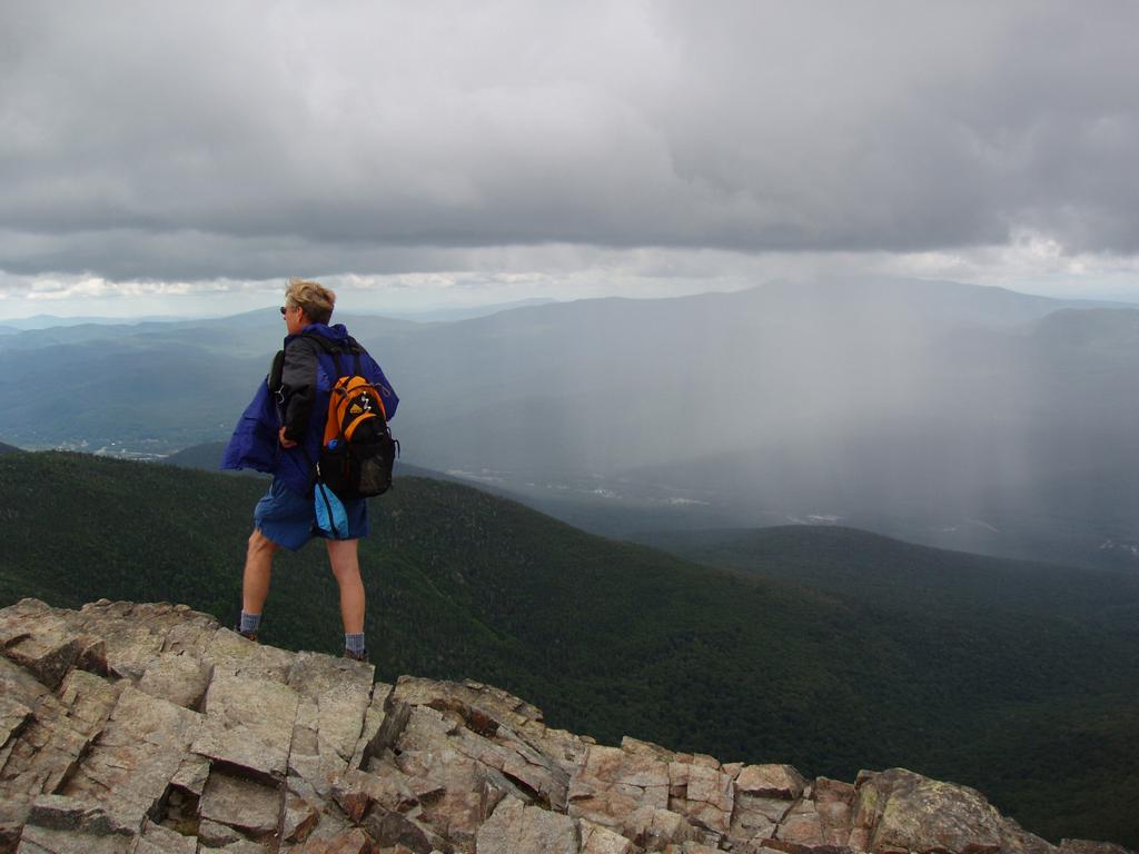 rain approaches from across Franconia Notch as Tom stands atop Mount Flume in the White Mountains of New Hampshire