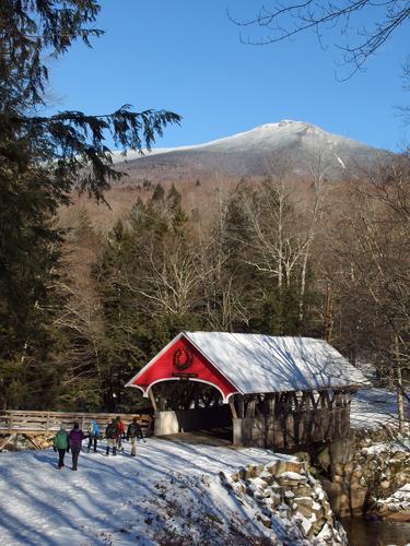 visitors head toward the Covered Bridge at Flume Gorge with Mount Liberty as a backdrop in New Hampshire