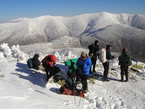 hikers in December enjoying a snowy view of Twin Mountains from Mount Garfield in New Hampshire