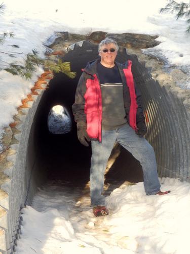winter hiker at the under-Route-101 tunnel on the Granite Town Rail Trail in New Hampshire