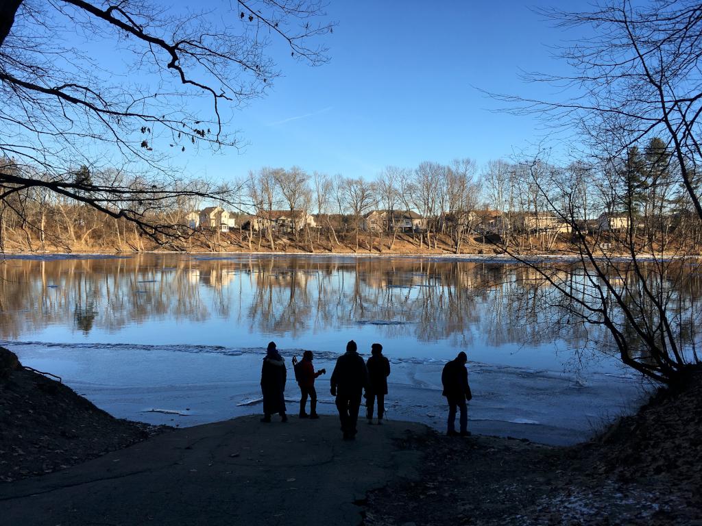 hikers in January on the Merrimack River boat ramp at Greeley Park in New Hampshire