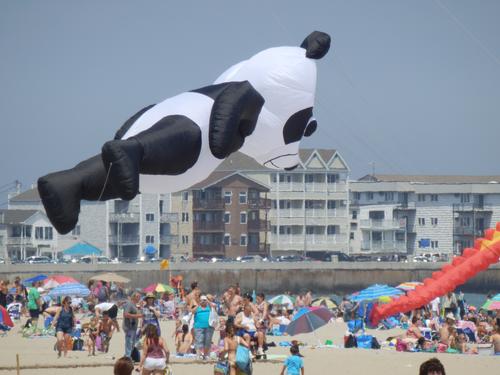 creative panda balloon-kite floats above a crowd of beachgoers at Hampton Beach in New Hampshire