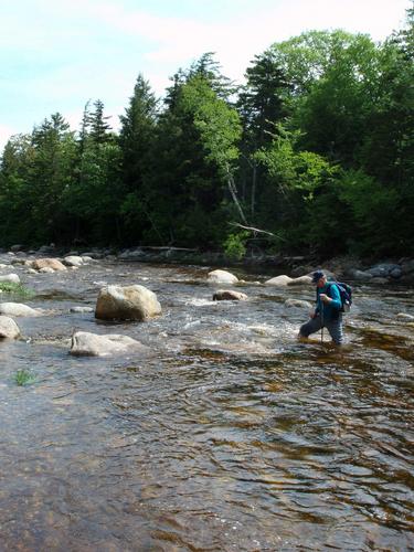 hiker fording Wild River on the way to Howe Peak in New Hampshire
