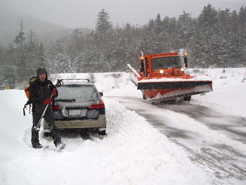 winter hiker and snowplow at the Kancamagus Pass parking lot in New Hampshire
