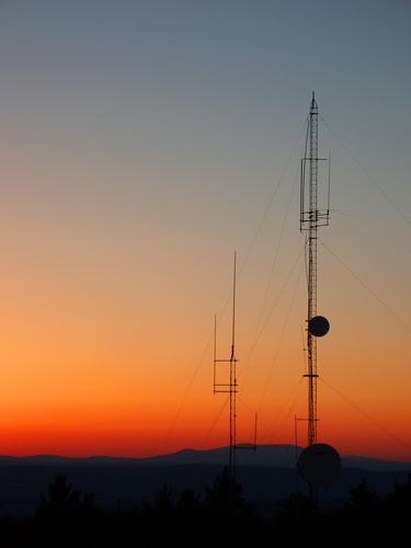 the sun sets behind communication towers as seen from Hyland Hill in western New Hampshire