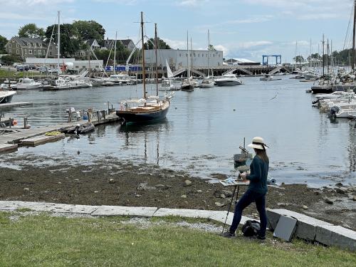 artist in July painting a boat in Camden Harbor near Islesboro Island in Maine