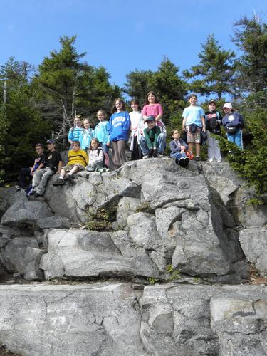 young hikers posing for a photo on a trailside cliff at Mount Kearsarge in New Hampshire