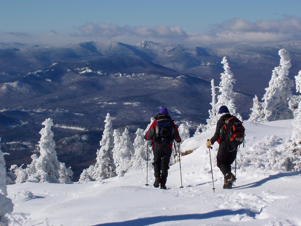 hikers head down trail in December amidst rime-coated trees and a fabulous view on Kearsarge North in the White Mountains of New Hampshire