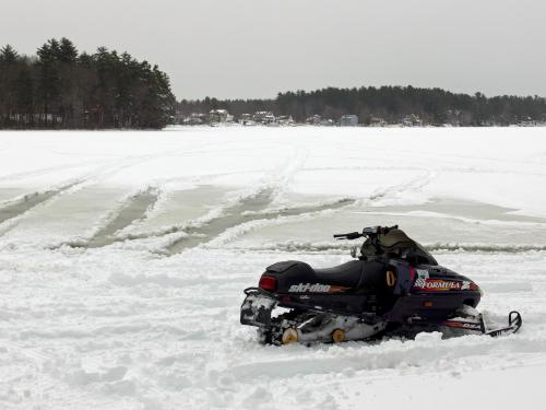 snowmobile and wet pond tracks in February at Kingston State Park in southeast New Hampshire