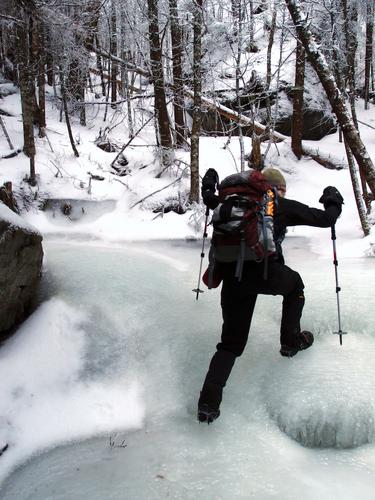 hiker ascending an icy section of the Mount Kinsman Trail in New Hampshire