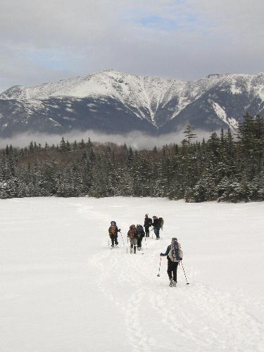 hikers snowshoe across Lonesome Lake in New Hampshire