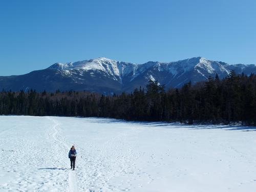 a winter hikers crosses Lonesome Lake on the way to Kinsman Mountain in New Hampshire