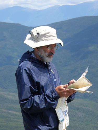 hiker with map on the summit of Mount Lafayette in New Hampshire