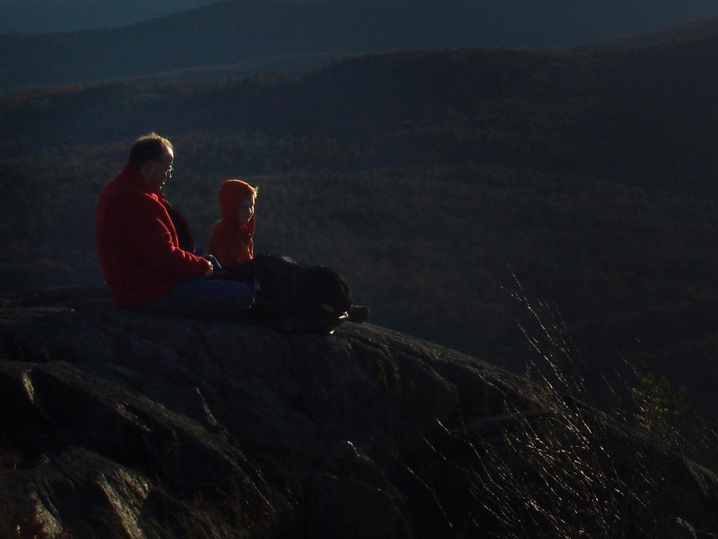 father and son watching sunset from atop Winn Mountain in New Hampshire
