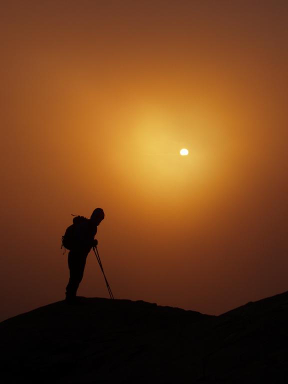hiker and storm-obscured sun on Mount Lafayette in New Hampshire