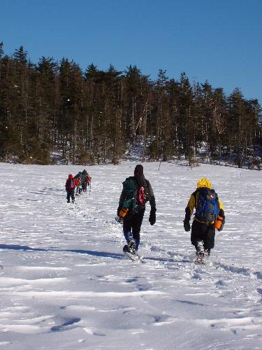 winter hikers crossing Norcross Pond near Mount Lowell in New Hampshire