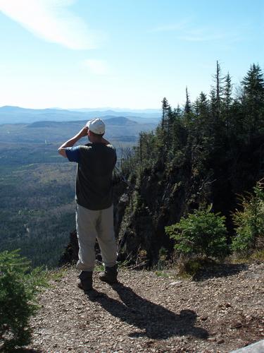 hiker and view from Magalloway Mountain's east cliff in New Hampshire