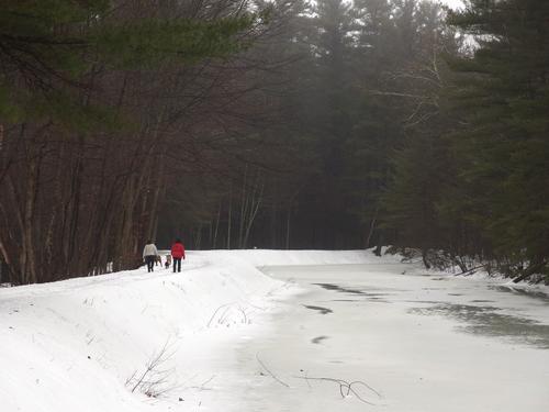 winter walkers along Nashua Canal at Mine Falls Park in New Hampshire