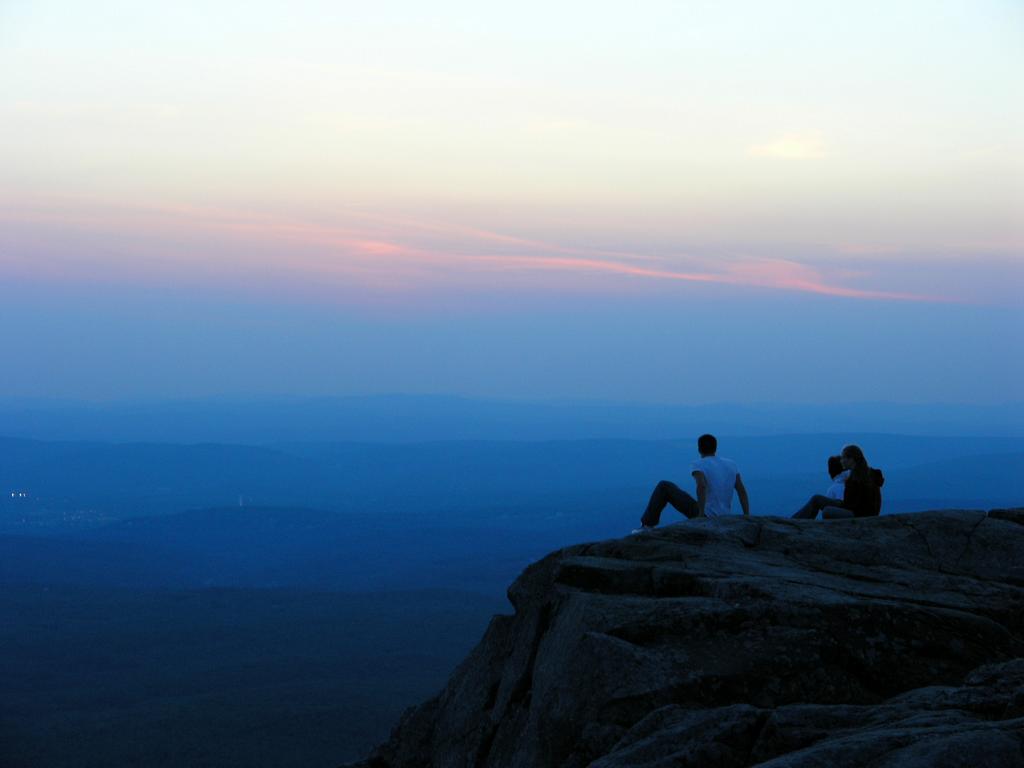 three hikers enjoy the twilight view on the 4th of July from Mount Monadnock in New Hampshire
