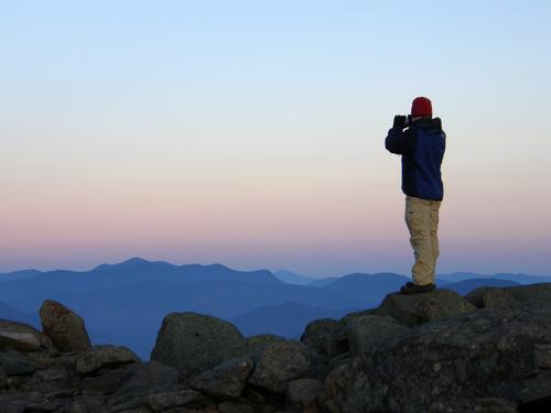Jeremy perches up high to photograph the sunset view from Mount Moosilauke in New Hampshire
