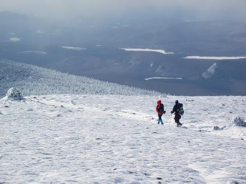 Betsy and Chris head down trail in February through a windswept icy landscape on Mount Moosilauke in New Hampshire